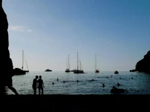 A couple of people standing next to a body of water